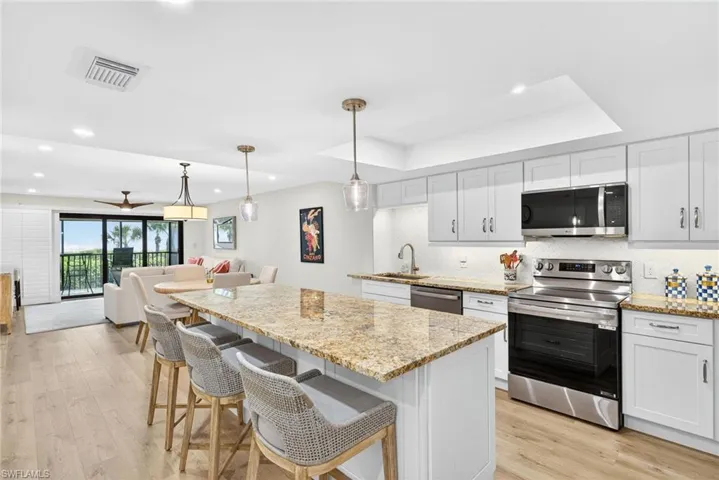 Kitchen with appliances with stainless steel finishes, white cabinets, decorative backsplash, light stone countertops, and recessed lighting