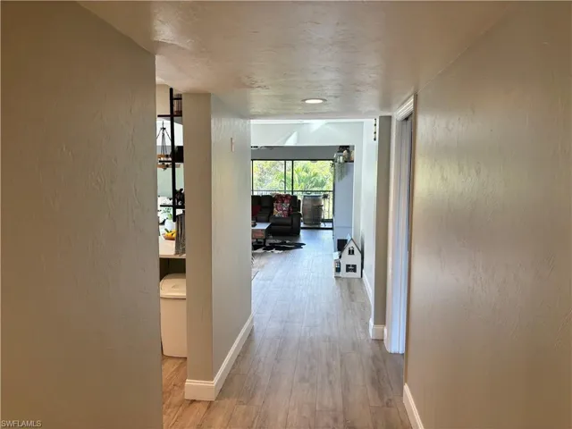 Hallway featuring a textured wall and light wood-type flooring