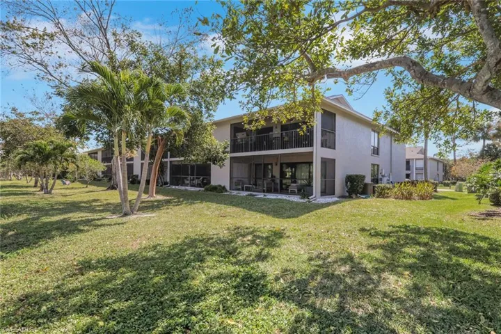 Rear view of house with a sunroom, stucco siding, a yard, and a balcony