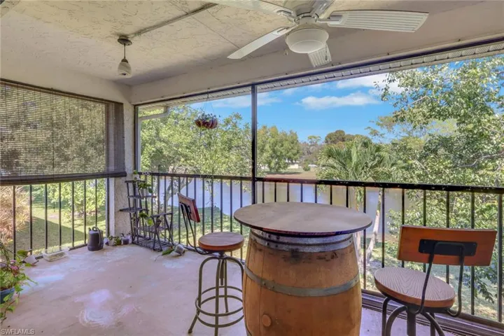 Sunroom with ceiling fan, a balcony, and a water view