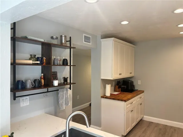 Kitchen with butcher block counters, white cabinetry, dark wood-type flooring, open shelves, and recessed lighting