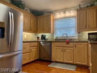 Kitchen with light brown cabinets, appliances with stainless steel finishes, sink, and tasteful backsplash