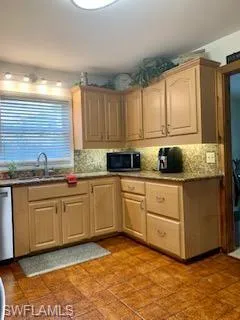 Kitchen with sink, light brown cabinets, stainless steel appliances, and backsplash