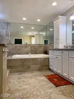 Bathroom featuring a relaxing tiled tub and vanity