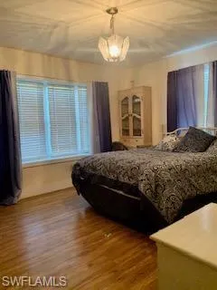 Bedroom with wood-type flooring, a chandelier, and multiple windows