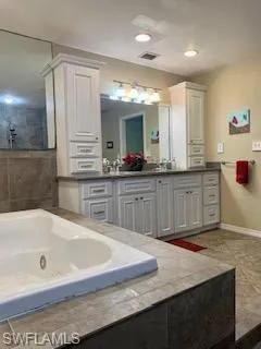 Bathroom with vanity, tiled bath, and tile patterned flooring