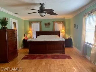Bedroom with ceiling fan, light wood-type flooring, and crown molding