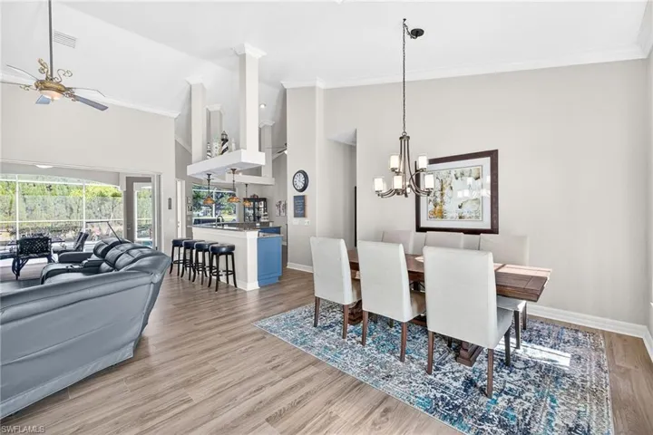 Dining room with light wood-style flooring, high vaulted ceiling, crown molding, a chandelier, and a ceiling fan