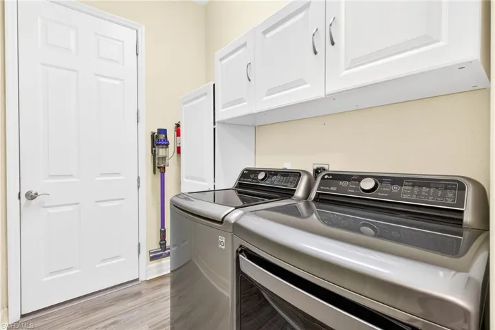 Laundry room featuring cabinet space, separate washer and dryer, and light wood-style floors