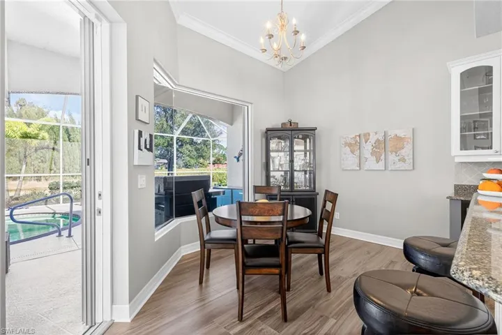 Dining area featuring light wood-type flooring, a sunroom, a chandelier, crown molding, and a high ceiling