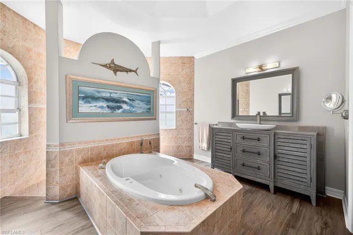 Full bath with a whirlpool tub, vanity, wood finished floors, and tile walls