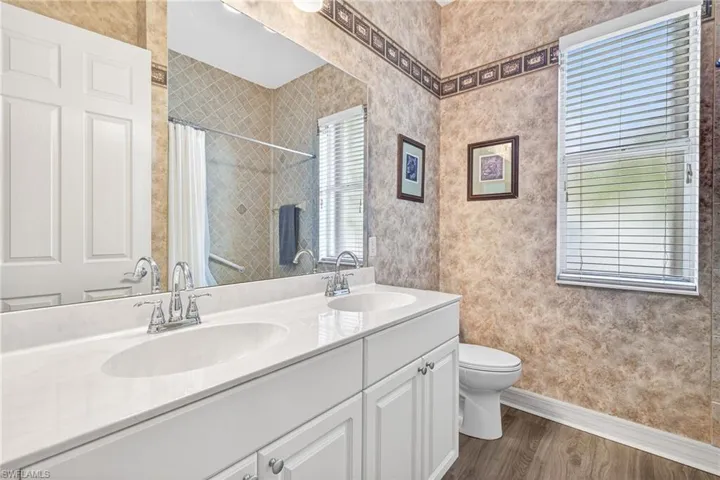Bathroom featuring double vanity, dark wood-style flooring, and a shower with shower curtain