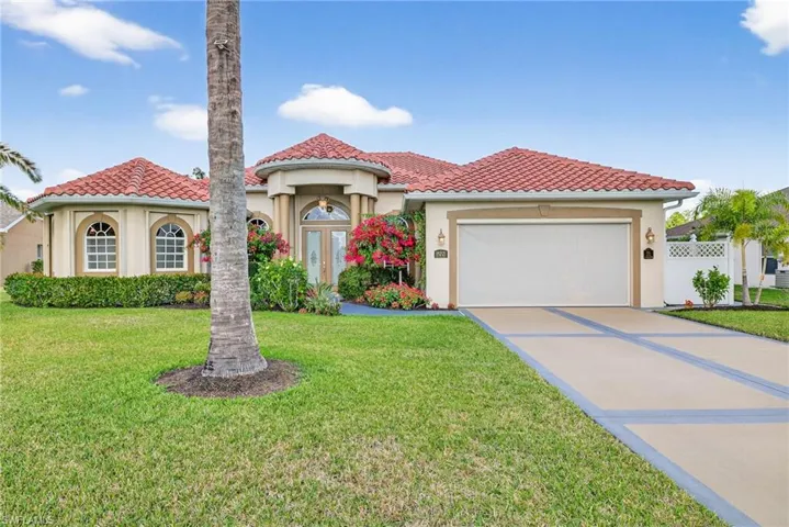 Mediterranean / spanish house featuring stucco siding, driveway, a tile roof, and a front yard