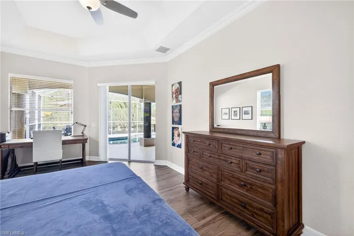 Bedroom featuring multiple windows, access to exterior, a ceiling fan, crown molding, and a raised ceiling