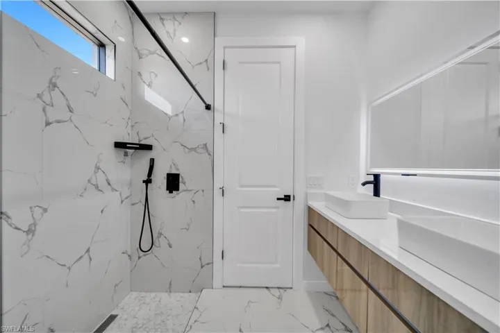 Bathroom featuring double vanity and a marble finish shower