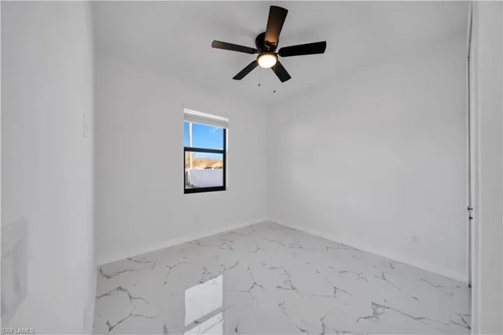 Spare room featuring light marble finish floors and ceiling fan