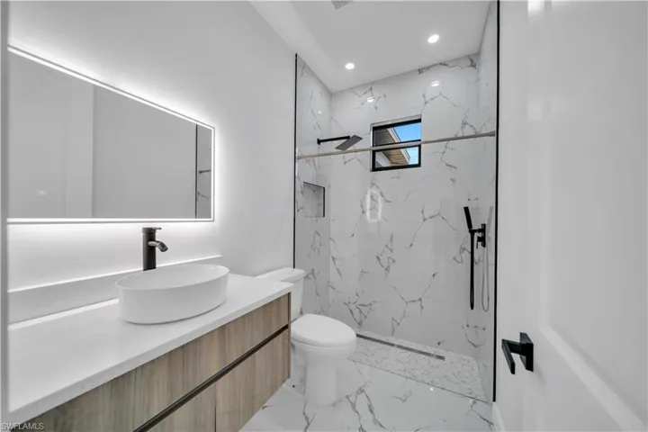 Full bath featuring vanity, a marble finish shower, recessed lighting, and light marble finish floors