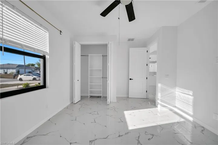 Unfurnished bedroom with light marble finish floors, a closet, and ceiling fan