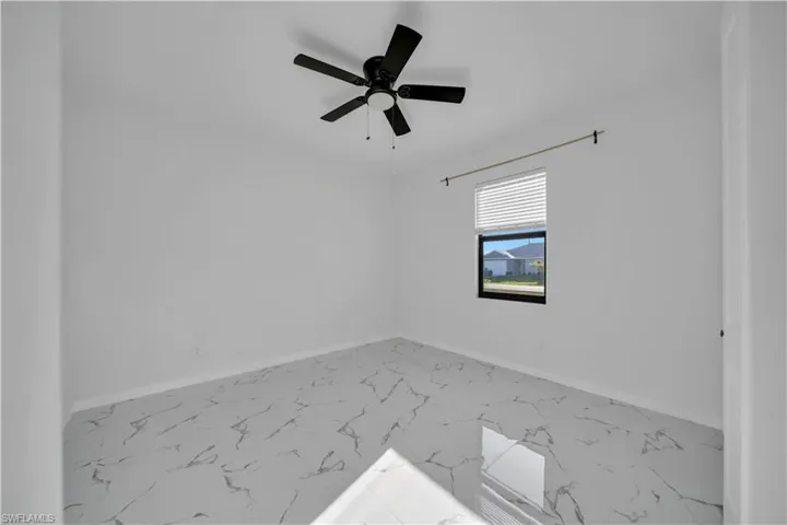Unfurnished room with ceiling fan and light marble finish flooring