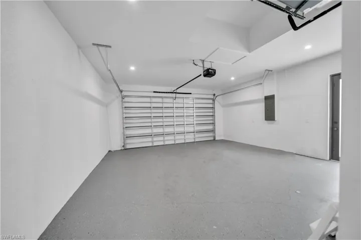 Garage featuring electric panel, recessed lighting, and a garage door opener