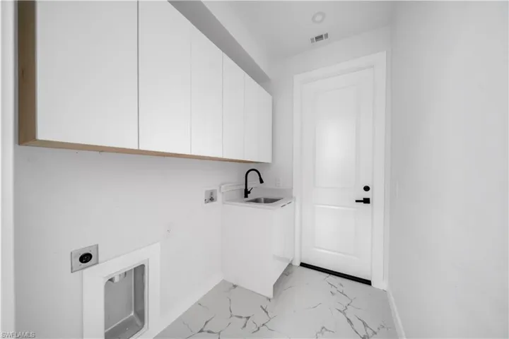 Laundry area with hookup for a washing machine, light marble finish floors, electric dryer hookup, and cabinet space