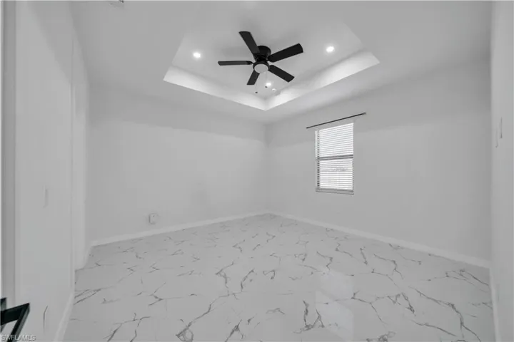 Empty room with a ceiling fan, a tray ceiling, and recessed lighting