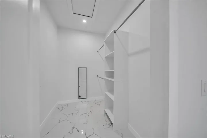 Walk in closet with attic access and light marble finish floors