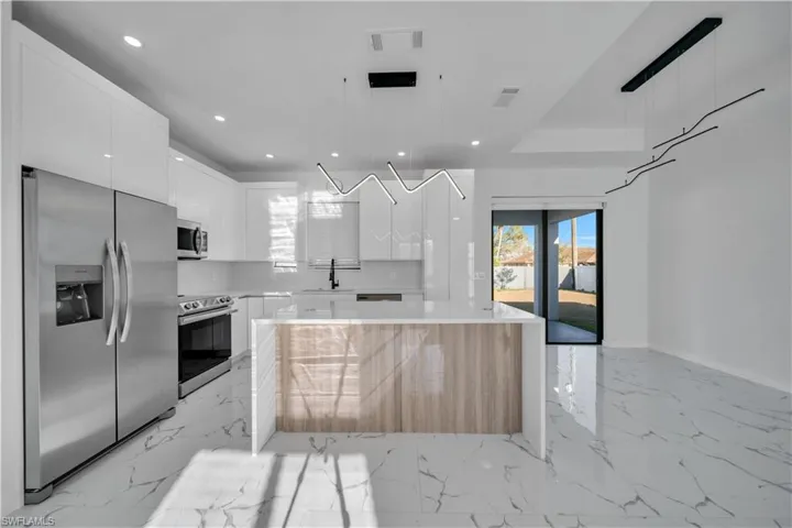 Kitchen featuring stainless steel appliances, modern cabinets, a kitchen island, and white cabinetry