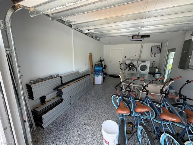 Spacious garage featuring an epoxy-coated concrete floor, laundry hookups with utility sink, and a built-in wall-mounted water heater