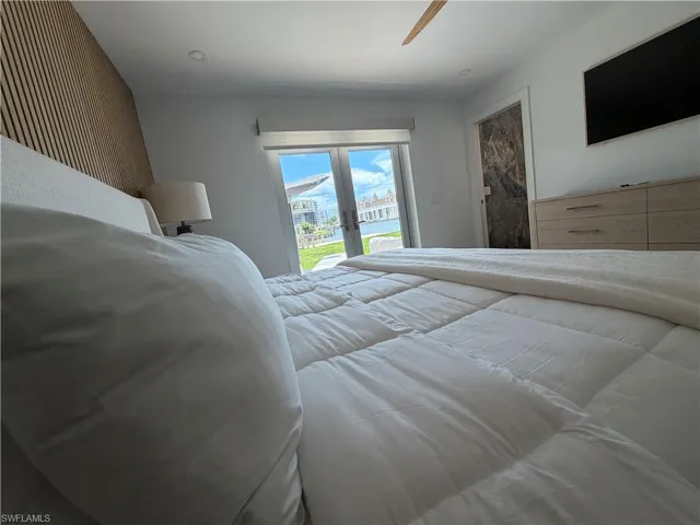 Bedroom featuring direct outdoor access through glass doors, a wood slat accent wall, recessed lighting, a ceiling fan, and a built-in light wood-finish dresser