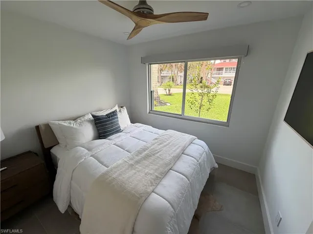 Contemporary bedroom featuring a wood-finish ceiling fan, recessed lighting, and a large window overlooking a landscaped exterior