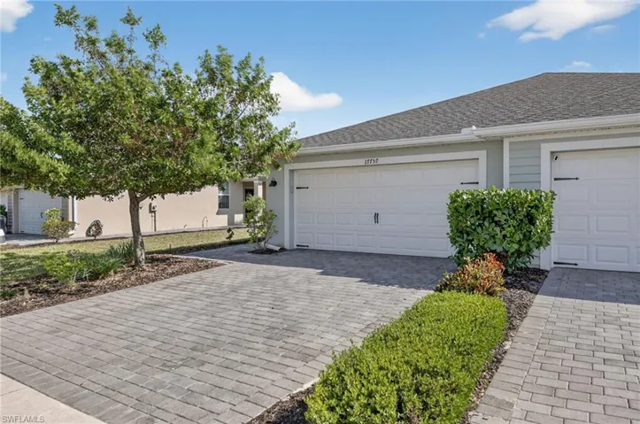 Ranch-style house with decorative driveway, an attached garage, roof with shingles, and stucco siding