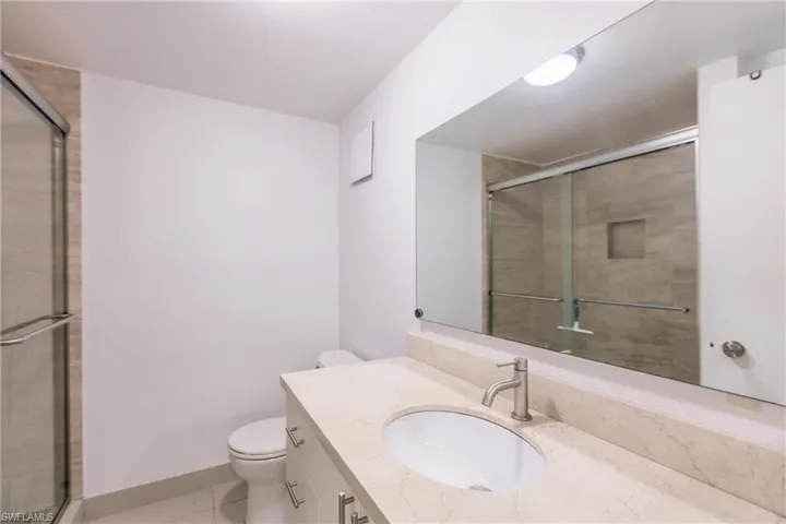 Bathroom with tile patterned flooring, vanity, toilet, and a shower with shower door