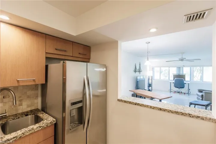 Kitchen with ceiling fan, hanging light fixtures, sink, tasteful backsplash, and stainless steel fridge with ice dispenser