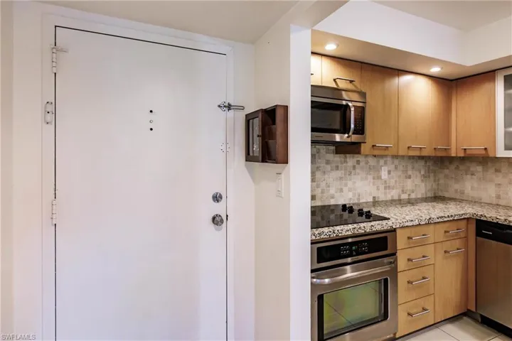 Kitchen featuring light stone counters, appliances with stainless steel finishes, backsplash, and light tile patterned floors