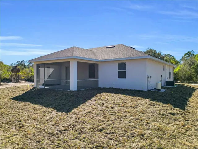 Rear view of house with stucco siding, a yard, a sunroom, and roof with shingles