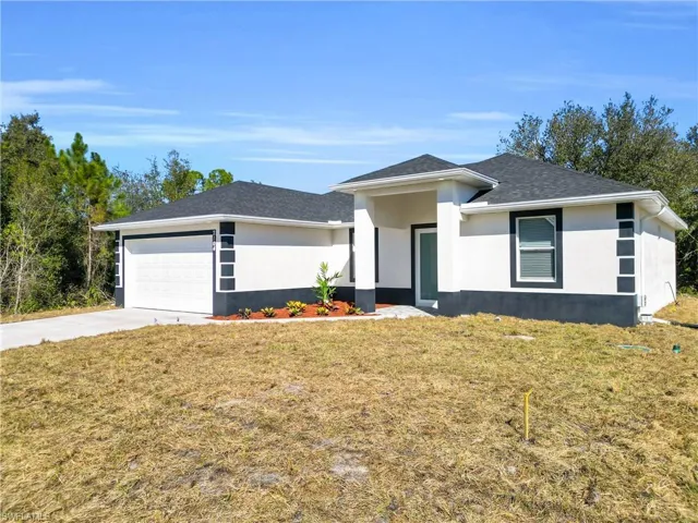 Prairie-style home featuring a front lawn, a garage, driveway, and stucco siding