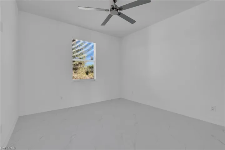 Unfurnished room with marble finish floors and a ceiling fan