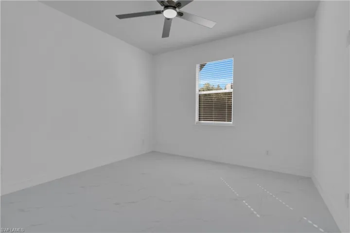 Unfurnished room with light marble finish floors and a ceiling fan