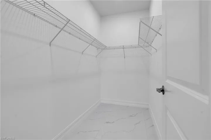 Walk in closet featuring light marble finish flooring