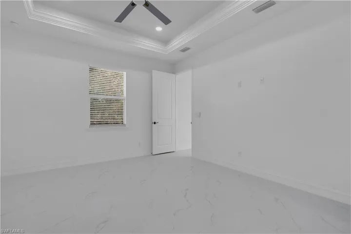 Empty room featuring marble look tiles, a tray ceiling, a ceiling fan, and recessed lighting