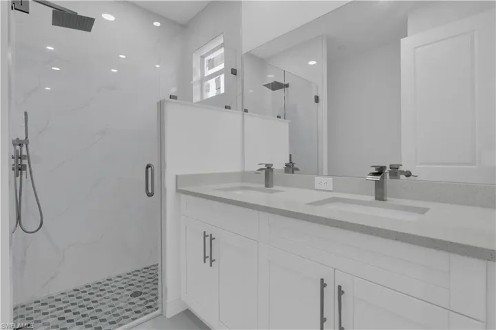 Full bathroom with a marble finish shower and double vanity