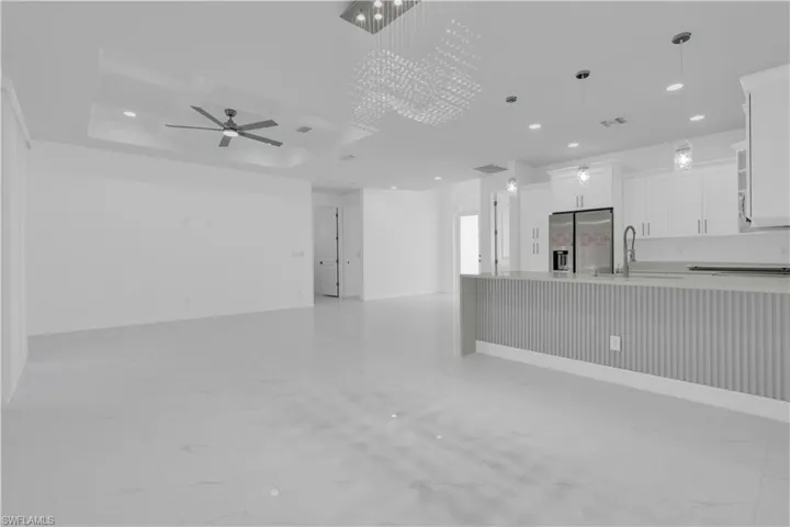 Kitchen with ceiling fan, white cabinets, decorative light fixtures, open floor plan, and stainless steel fridge with ice dispenser