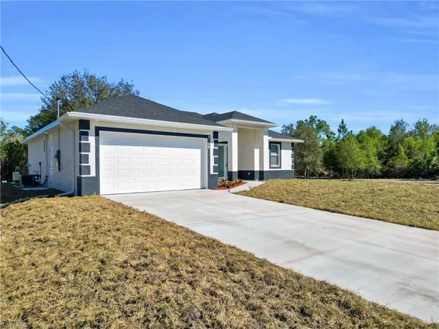 Ranch-style home featuring a front yard, a garage, concrete driveway, and stucco siding