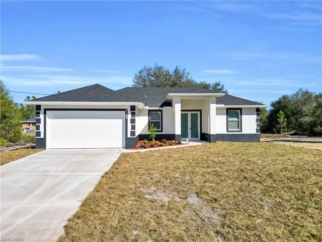 Prairie-style house with a front yard, concrete driveway, french doors, and an attached garage