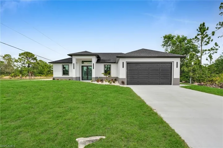 Prairie-style house featuring stucco siding, french doors, driveway, a front yard, and a garage
