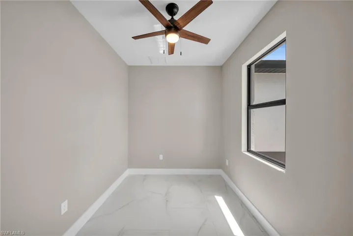 Unfurnished room with baseboards, marble finish floor, a ceiling fan, and plenty of natural light