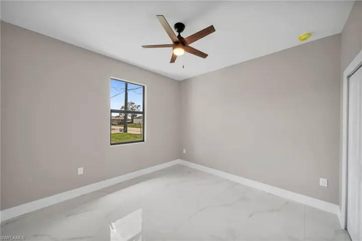 Spare room with marble finish floor, baseboards, and a ceiling fan