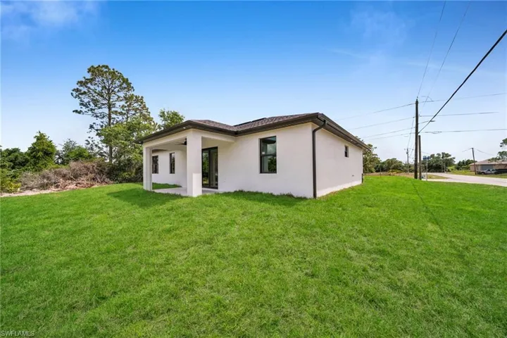 Back of house with a lawn, stucco siding, and a ceiling fan