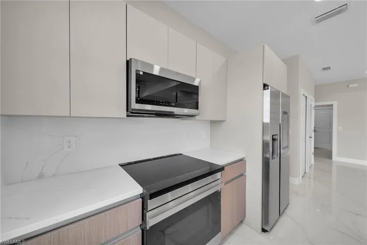 Kitchen featuring marble finish floor, baseboards, visible vents, and stainless steel appliances